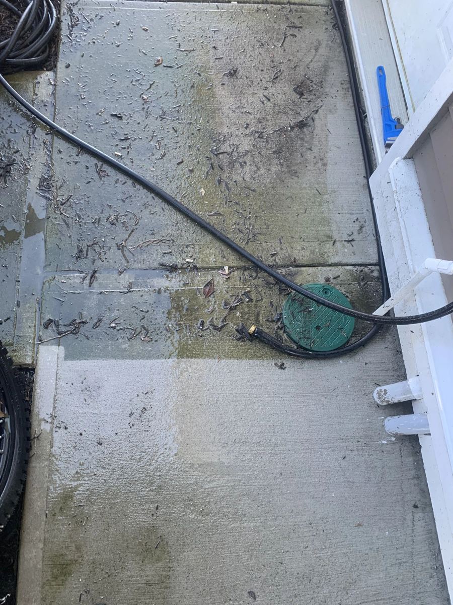 Concrete walkway being pressure washed, half cleaned